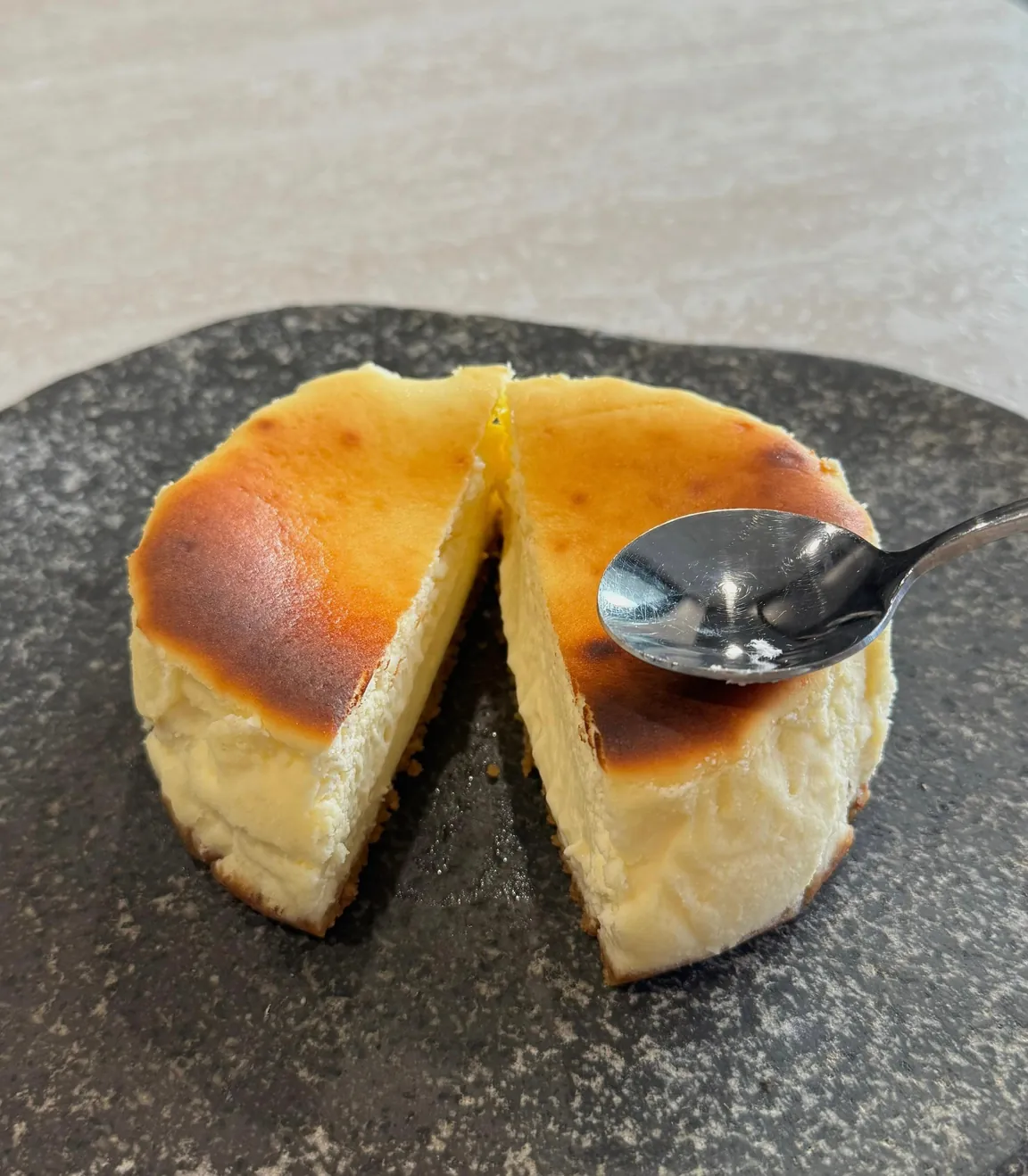 A Classic tartza cut in half on a stone slab, golden scorched top and creamy centre.