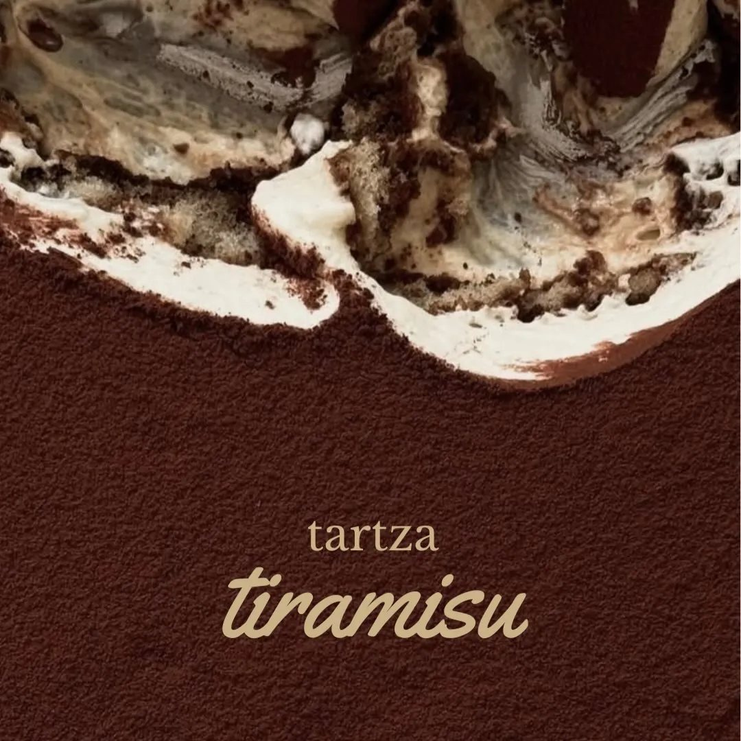 Close-up of tiramisu: mascarpone cream and a thick snow of cocoa.